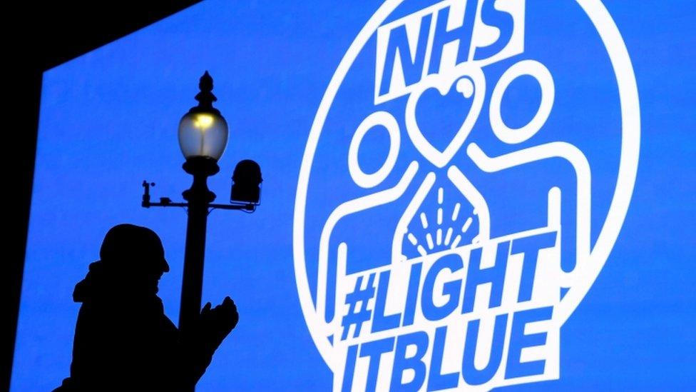 People applaud in front of big screen in Piccadilly Circus during the Clap For Our Carers campaign in support of the NHS