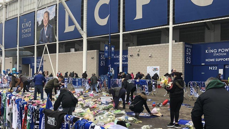 Volunteers move flowers and tributes