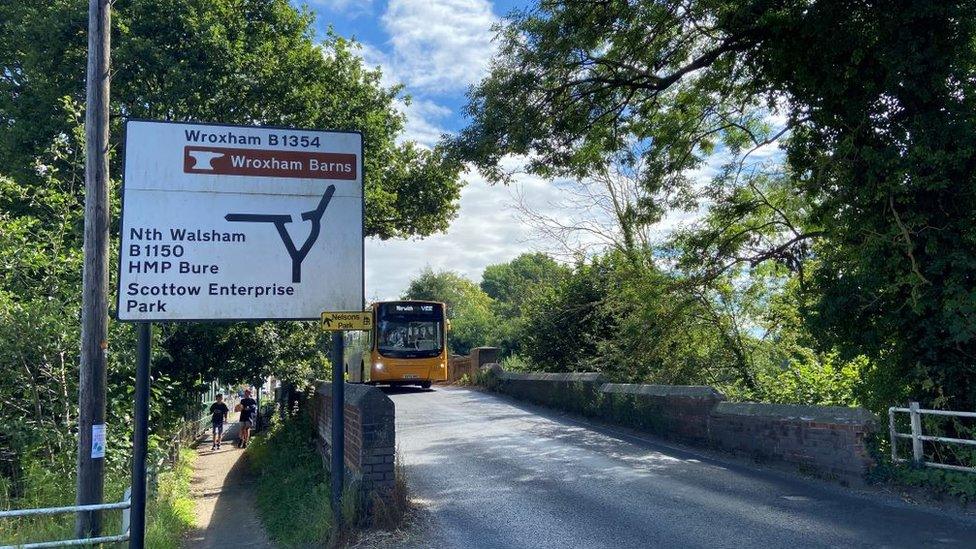 Bus approaching humpback bridge in village of Coltishall