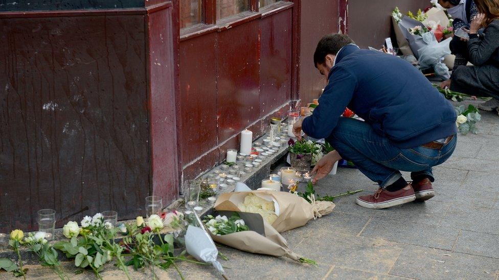 A man lights a candle outside Le Carillon bar, the scene of one of the attacks