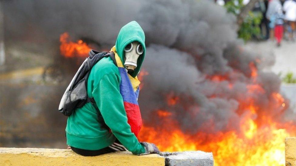 A demonstrator sits next to a fire barricade on a street during a rally against Venezuela's President Nicolas Maduro in Caracas, Venezuela April 24, 2017.