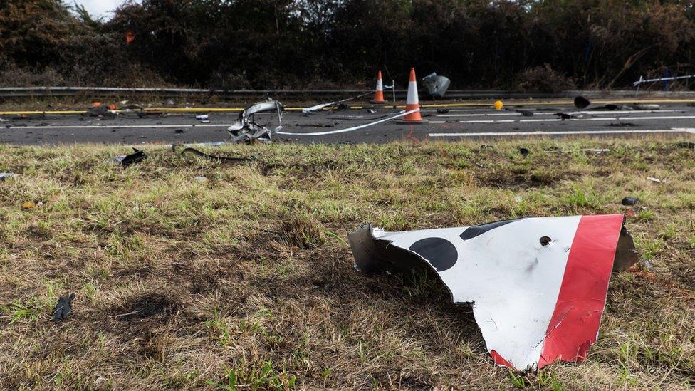 A broken road sign lies near the road where the plane crashed