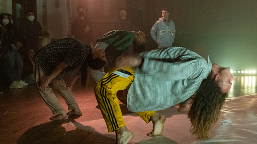 Dancers perform in front of an audience.