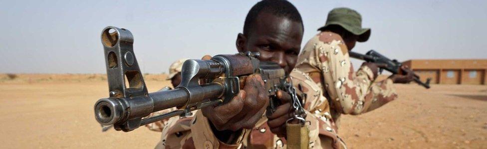 Two African soldiers aim guns in the desert