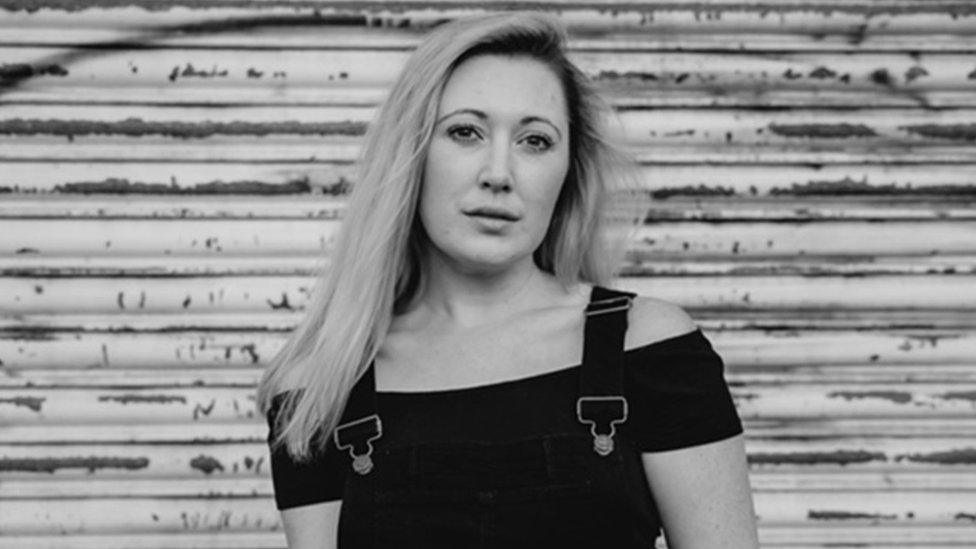 Black and white image of Melissa Johns in front of a garage