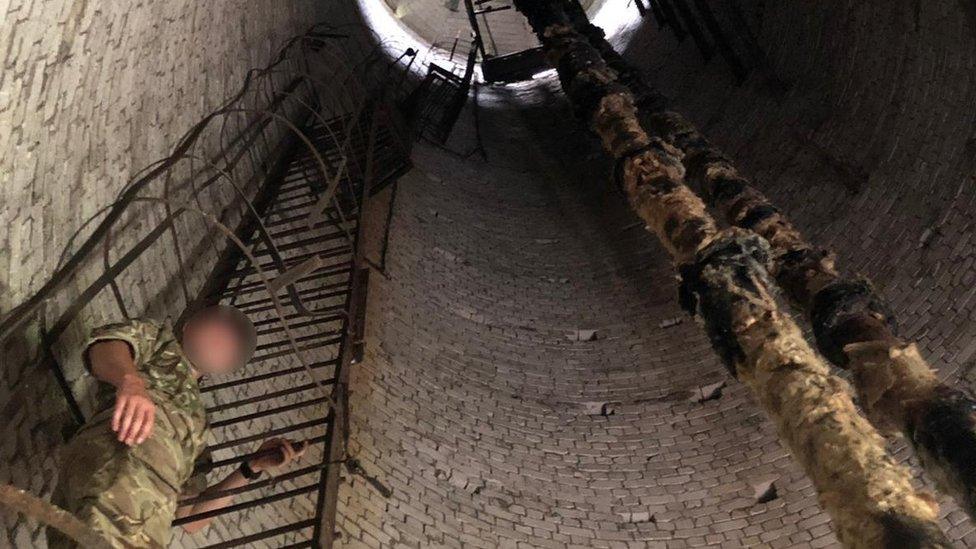 A commando inside a tower with degraded insulation around pipe work