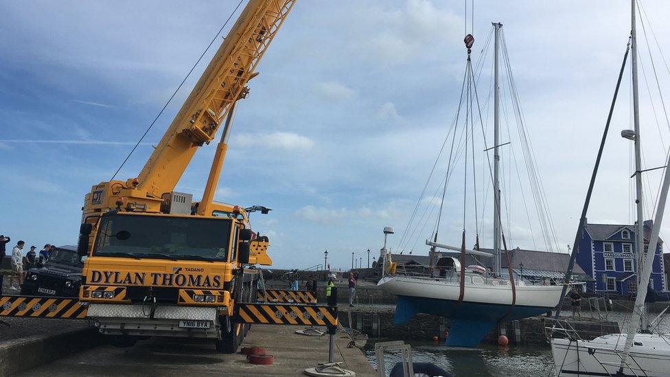 Craen yn gosod y cwch yn ôl i'r harbwr yn Aberaeron