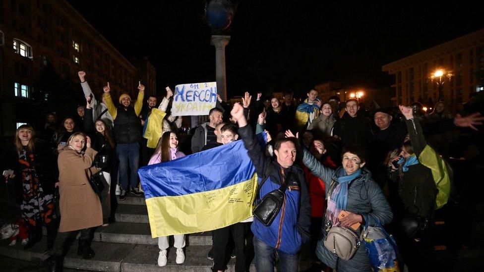 People hold a Ukranian flag and a slogan which reads as "11/11/2022 - Kherson - Ukraine" as they gather in Maidan Square, Kyiv to celebrate the liberation of Kherson