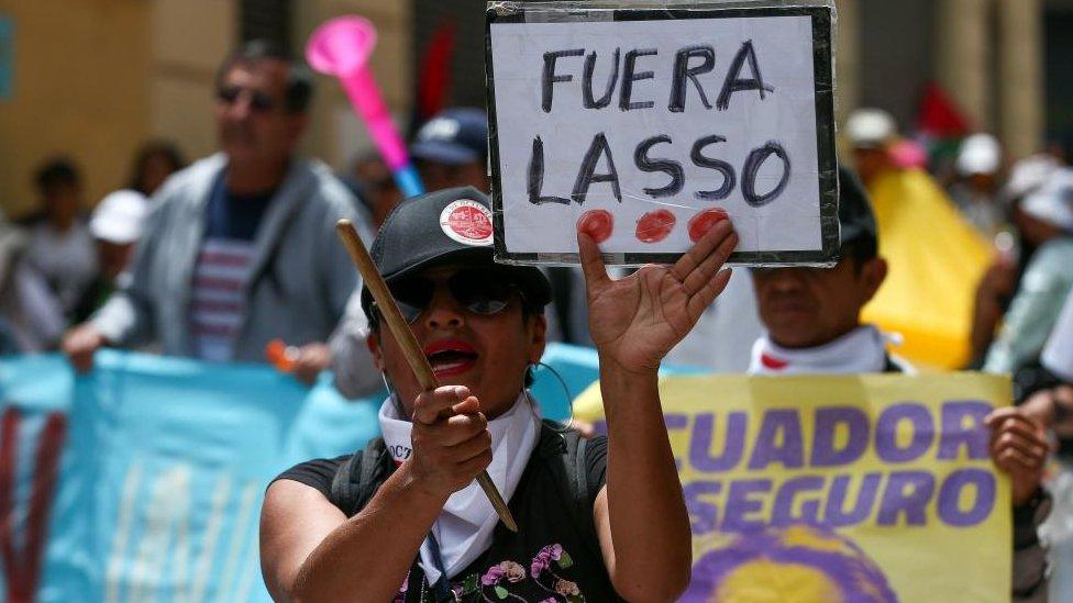 A woman holds a placard reading 'Lasso out' during a protest to demand better working conditions on the commemoration of the International Workers' Day in Quito, Ecuador, 01 May 2023.