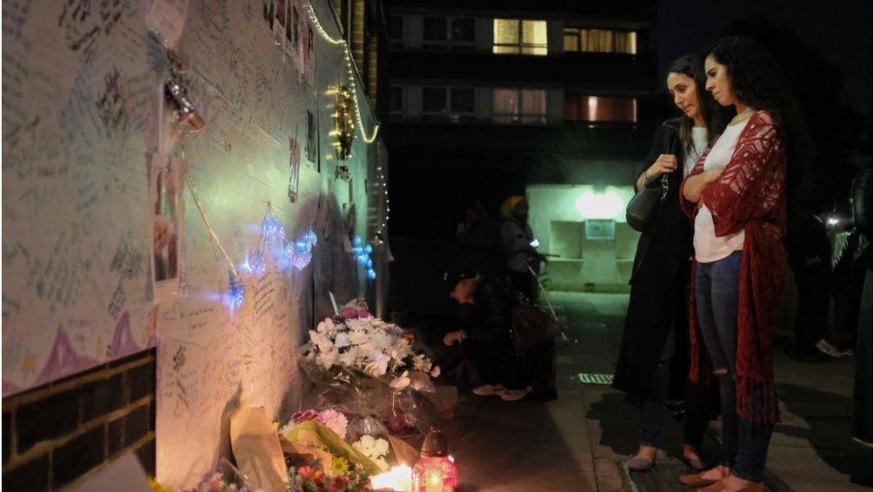 Women looking at a wall of condolence messages