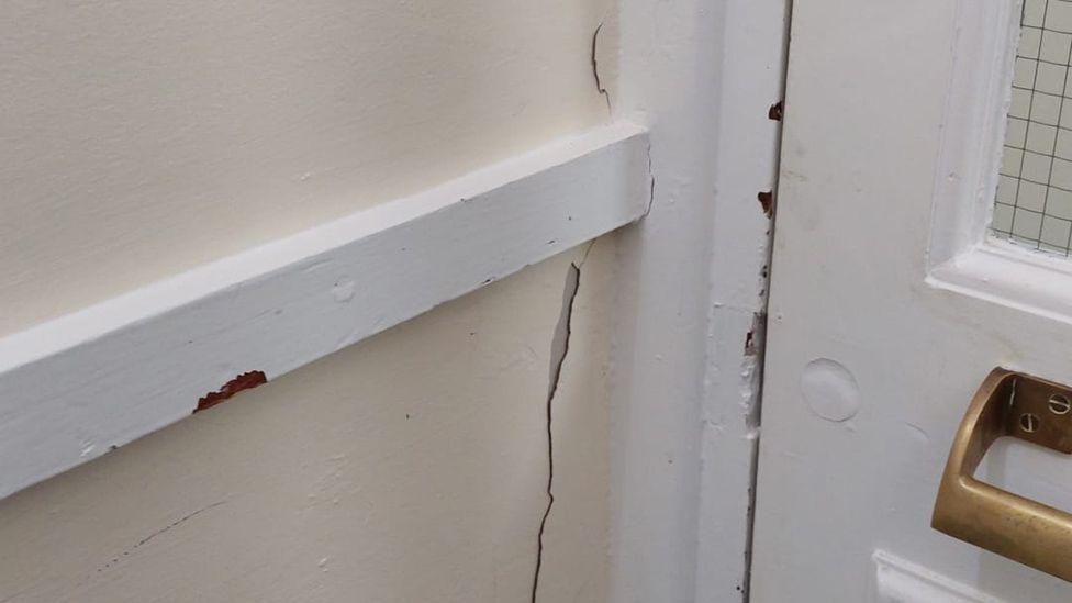 A crack to a wall next to a door