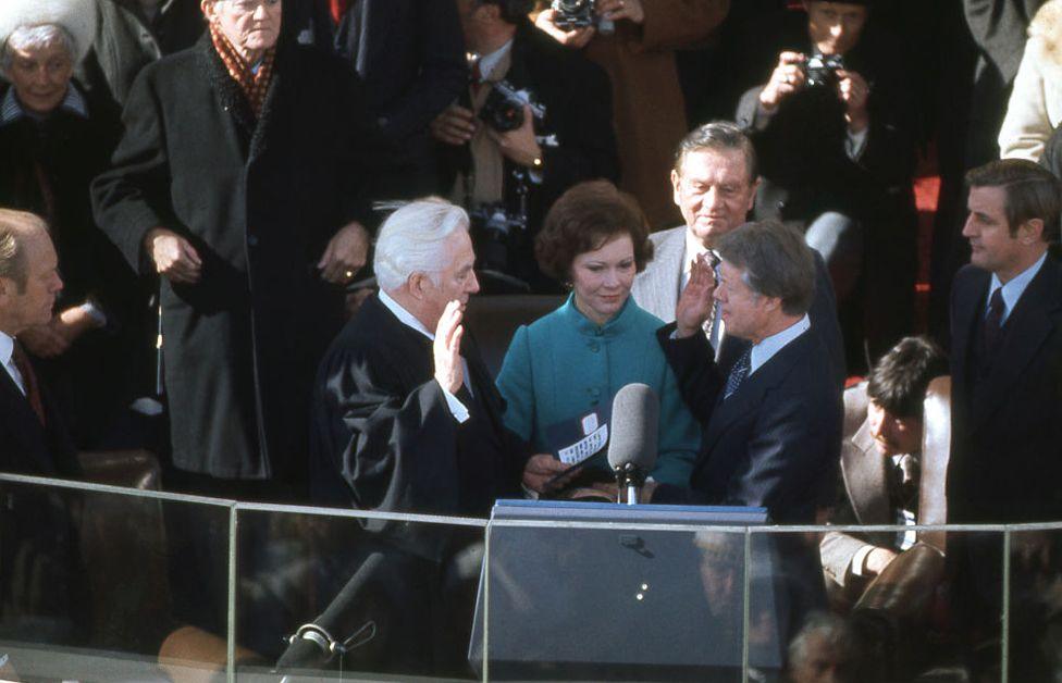 President Jimmy Carter takes the oath of office from Chief Justice of the Supreme Court Warren Burger on stage in front of the White House in January 1977