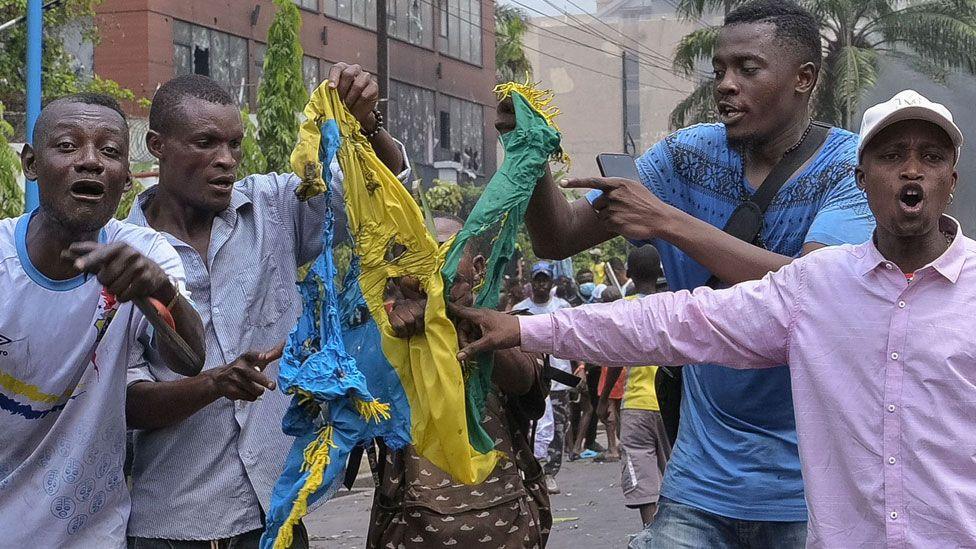 Five men in Kinshasa tear apart a Rwandan flag as they shout in protest about the M23's attack of Goma in DR Congo - 28 January 2025