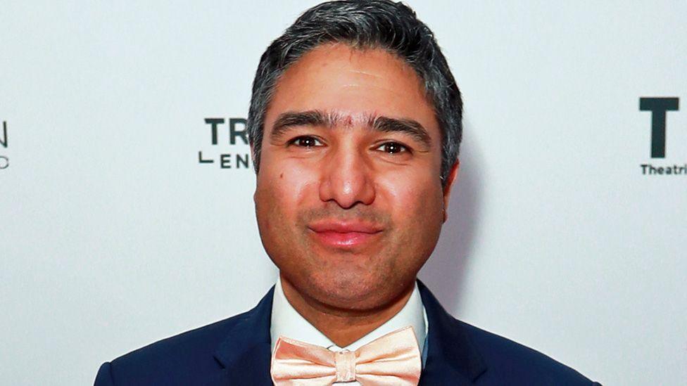 Nick Mohammed, wearing a blue suit and peach bowtie.