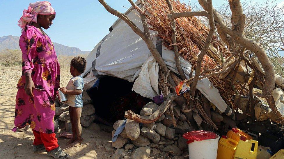 A woman and child stand outside their shelter at a camp for internally displaced people on the outskirts of the southern city of Taiz, Yemen, on 11 January 2017