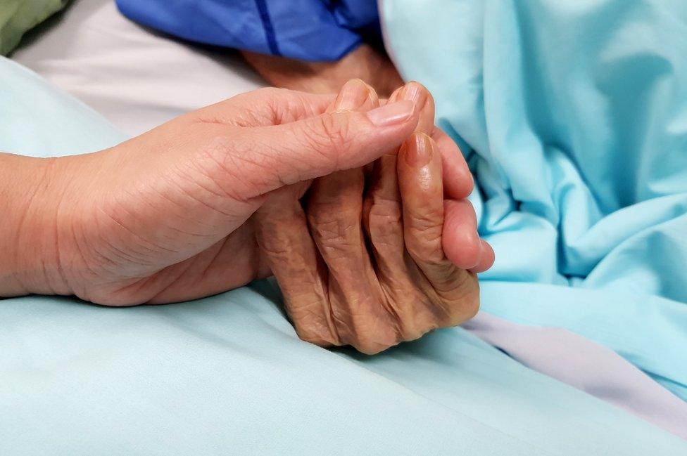 nurse holding patient's hand in hospital