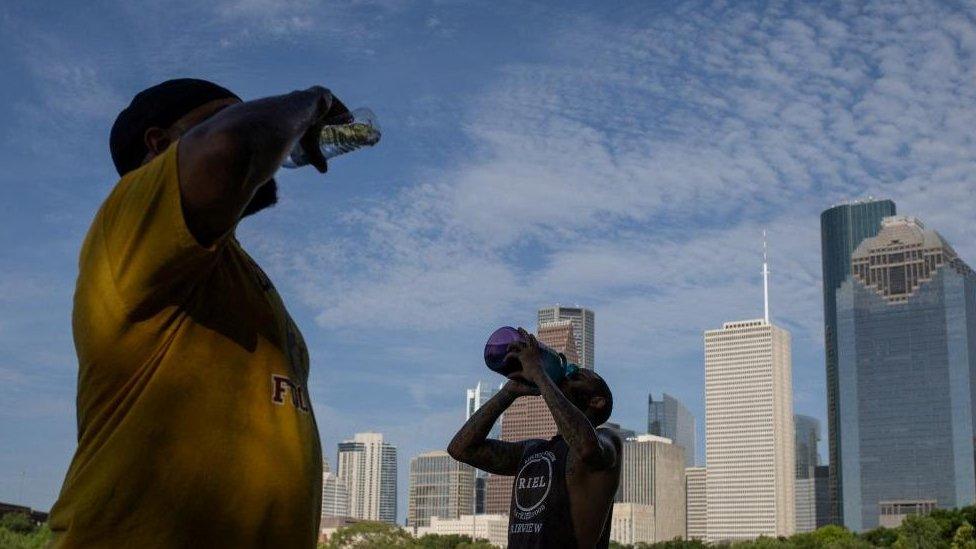 Val Martin and Ashford Joseph rehydrate after climbing stairs in Eleanor Tinsley Park as temperatures hit 100 degrees Fahrenheit in Houston, Texas, U.S., July 12, 2023.