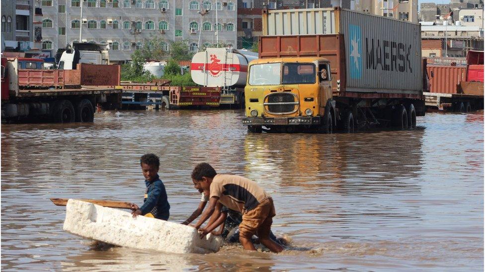 Children push a makeshift raft in a flooded street in Aden (22/04/20)