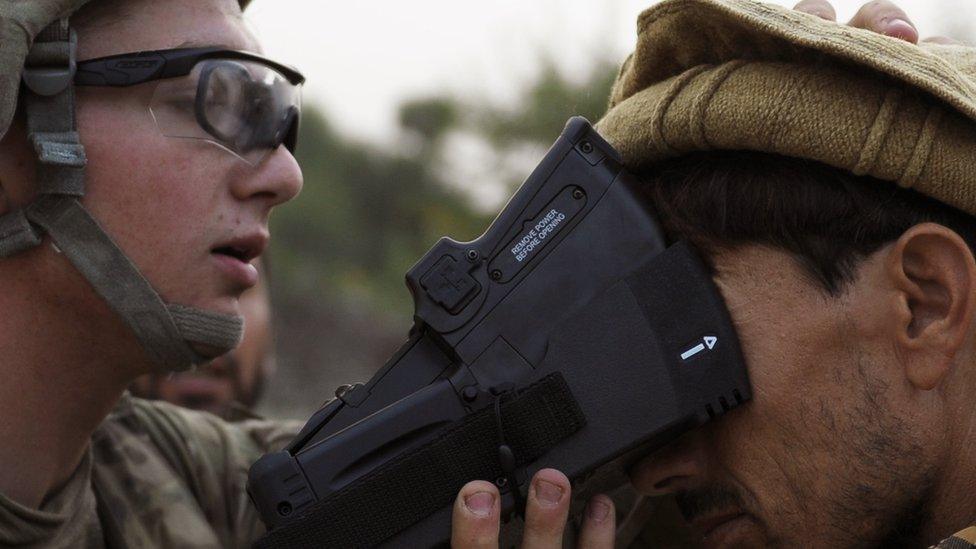 A US solider collects biometric information from a villager