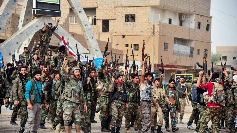 Handout picture from official Syrian Arab News Agency on November 21, 2017 shows members of the pro-Syrian government forces in a public square in the Syrian border town of Albu Kamal.