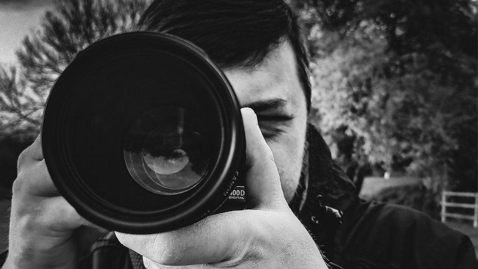 Benjamin Warburton taking a photo with a camera