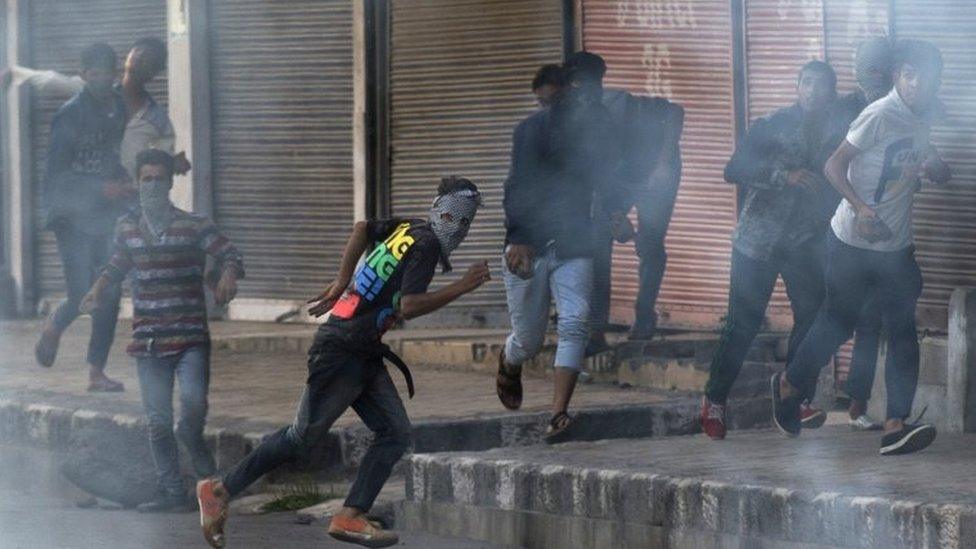 Kashmiri Muslim protesters chase Indian paramilitary soldiers as they walk back towards their base camp after a day long curfew in Srinagar, Indian controlled Kashmir, Saturday, Aug. 13, 2016.