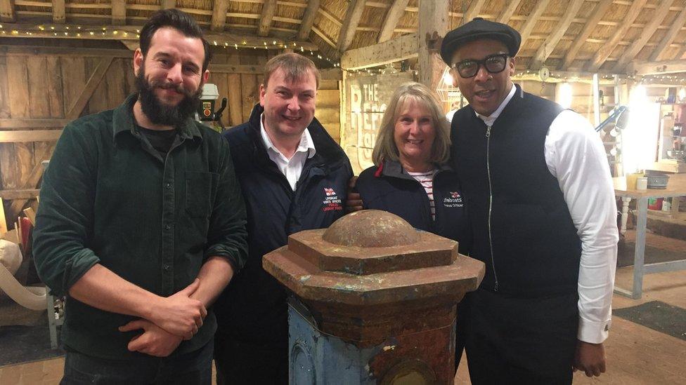 Volunteers Elaine Bawden and Martin Brockman with Jay Blades and Dominic Chinea behind restored collection box