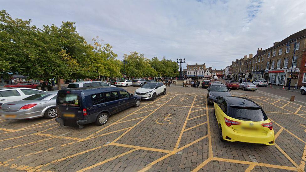 St Neots Market Square, pre-renovation, showing stacks of parked cars