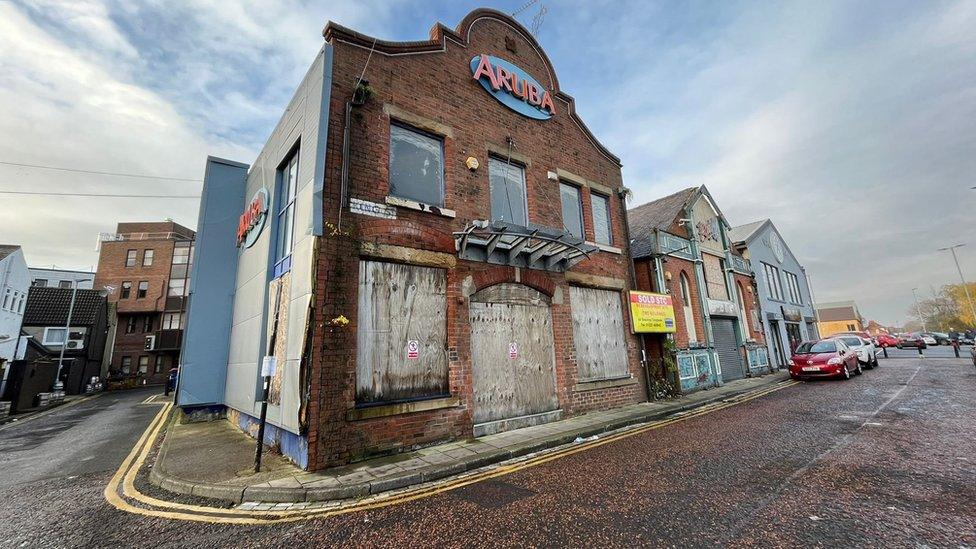 Two old derelict looking buildings with nightclub signs