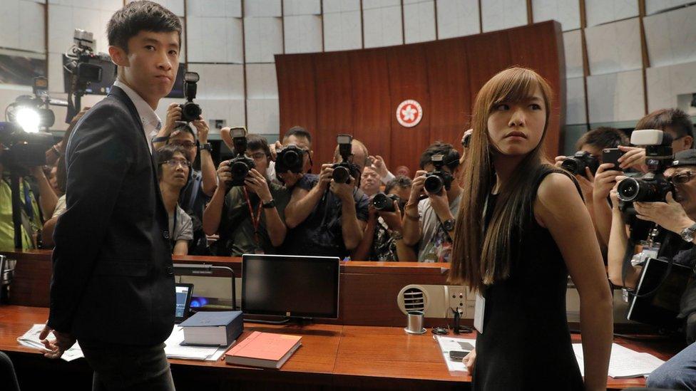 Newly elected Hong Kong lawmakers Yau Wai-ching, right, and Sixtus Leung, left, are surrounded by photographers at legislature council in Hong Kong Wednesday, Oct. 26, 2016