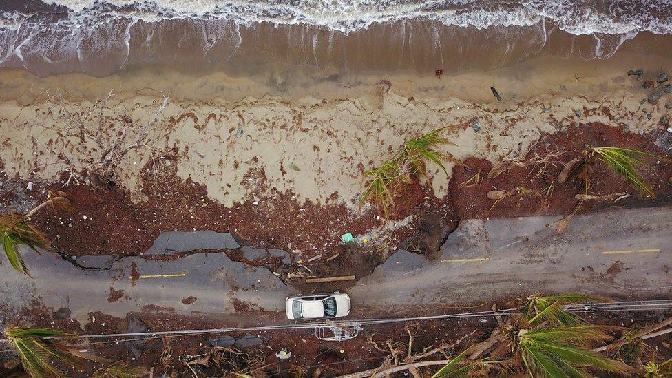 A car drives on a damaged road in the aftermath of Hurricane Maria in Humacao, Puerto Rico, on October 2, 2017