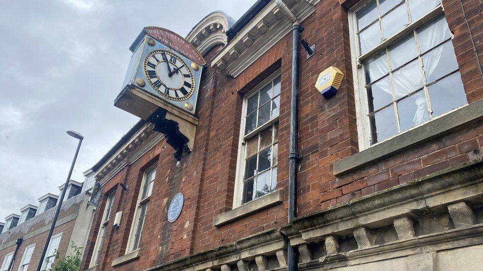 A close-up shot of a disused historic building number 27-28 Queen Street with a clock on it.  