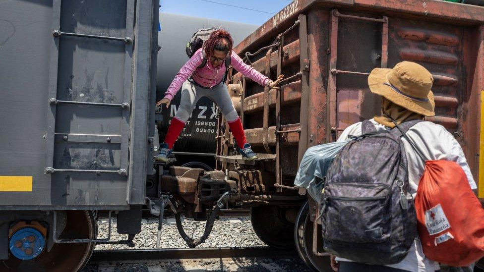 Immigrants climb down from a freight train en route to the U.S.-Mexico border on May 10, 2023 near Ciudad Juarez, Mexico