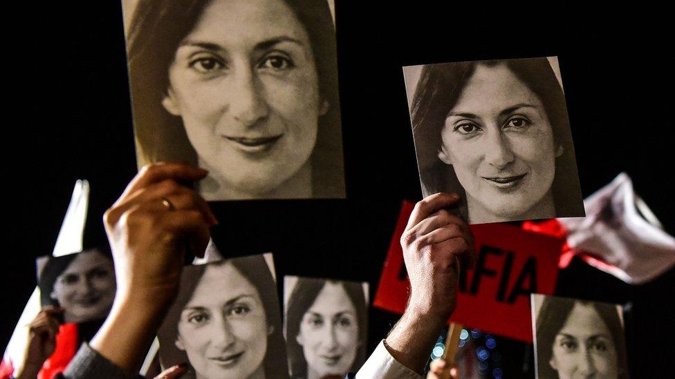 Protesters hold placards with images of the journalist