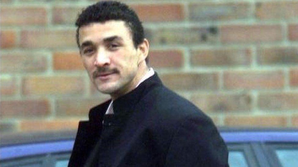 Brendon Fearon is looking towards a camera wearing a blue jacket. He has dark hair and a moustache