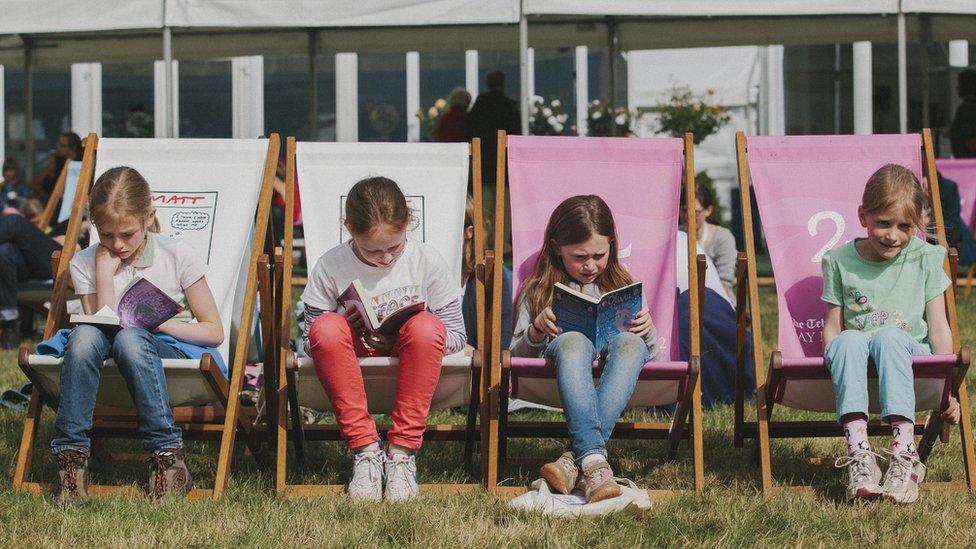 Children sitting in deckchairs reading books at Hay Festival