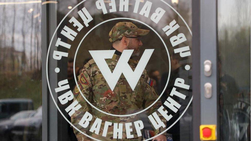 A man wearing a camouflage uniform walks out of PMC Wagner Centre, which is a project implemented by the businessman and founder of the Wagner private military group Yevgeny Prigozhin, during the official opening of the office block in Saint Petersburg,