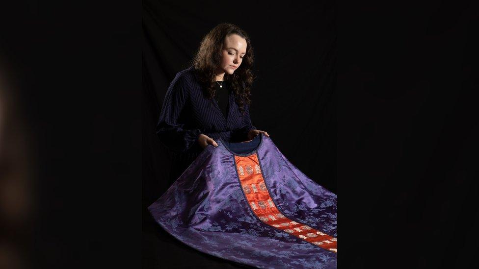 A woman holds a purple and red piece of clothing