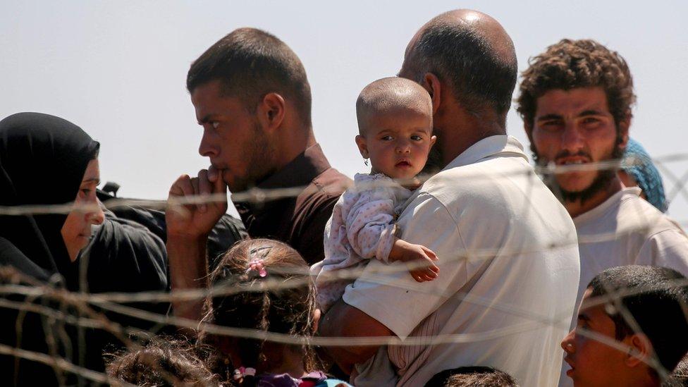 Displaced Syrians who have fled Raqqa stand at a temporary camp in the northern Syrian village of Ain Issa on 3 June 2017