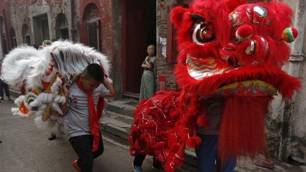 A member (C) of the Chinese community watches as performers carrying lion masks arrive to take part in the celebrations to mark the Chinese New Year in Kolkata