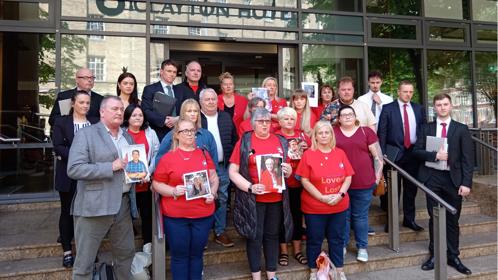 Group of people holding pictures of family members