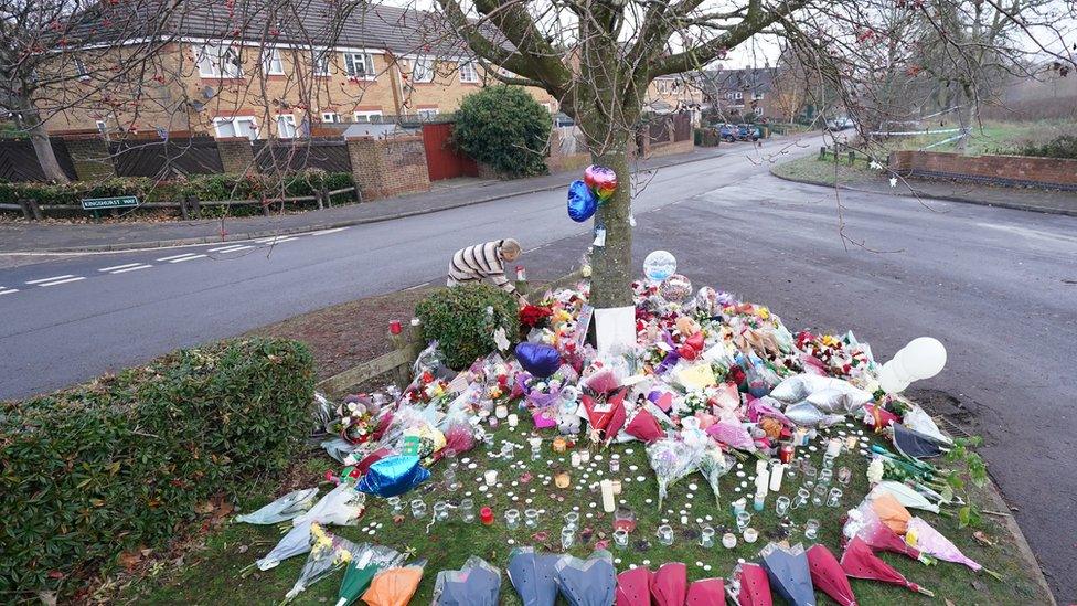 Floral tributes and candles at a tree