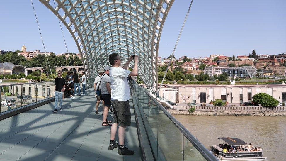 Tourists visit the Bridge of Peace at the old town of Tbilisi, Georgia 23 June 2019