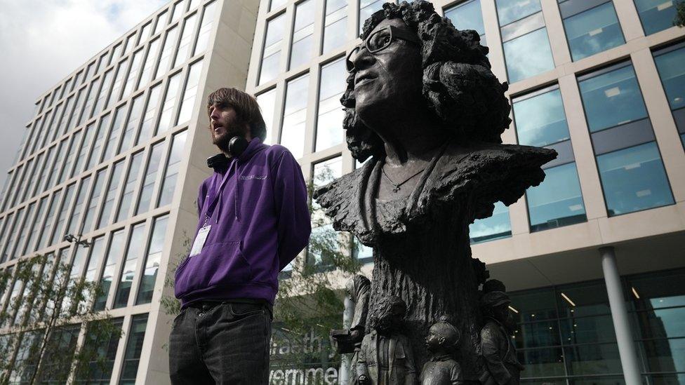 Johnny Giles standing beside the bronze stature of Betty Campbell in Cardiff