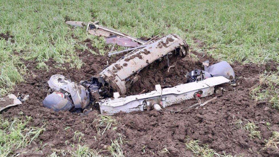 Grey-coloured parts from a Typhoon jet laying in a field covered in mud