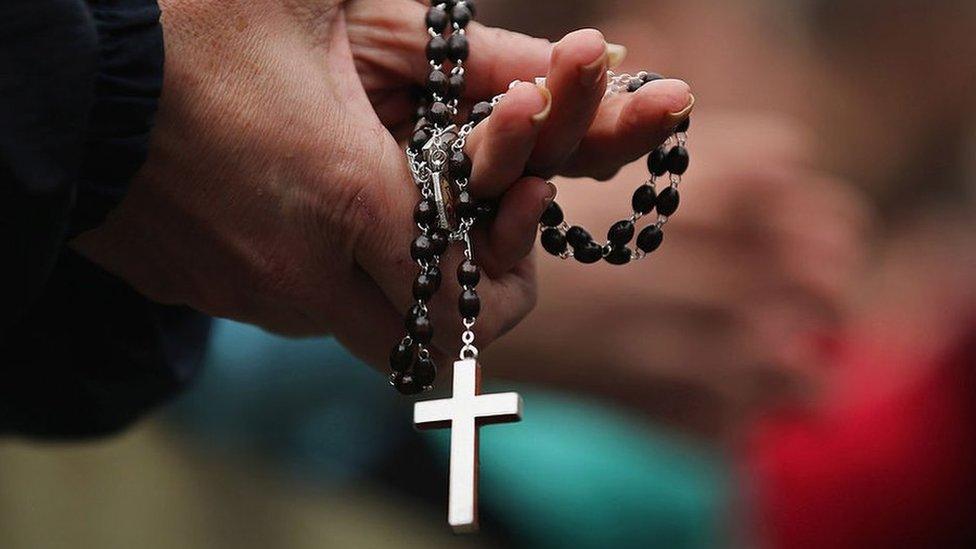 A woman holds rosary beads