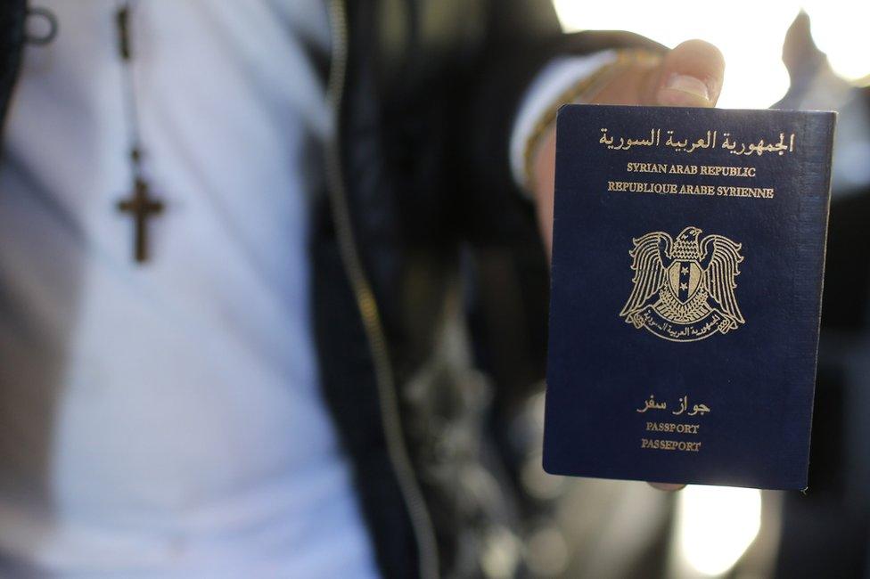 A man holds his Syrian passport