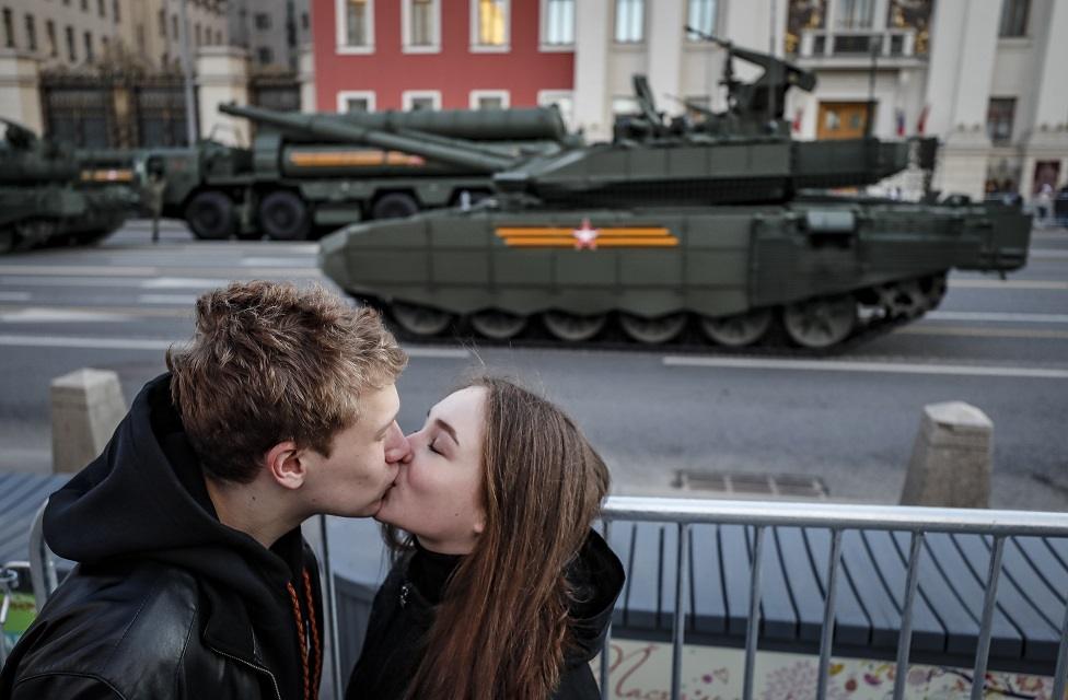 Couple kiss in front of tanks