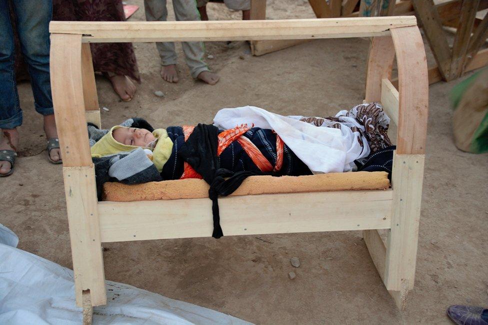 Baby in a home-made cot in a refugee camp