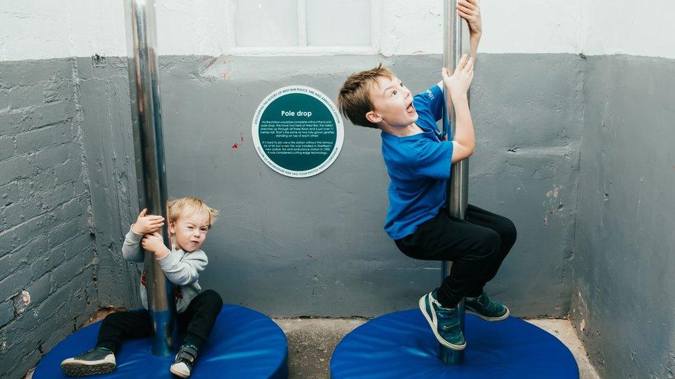 Young boys sliding down fire poles